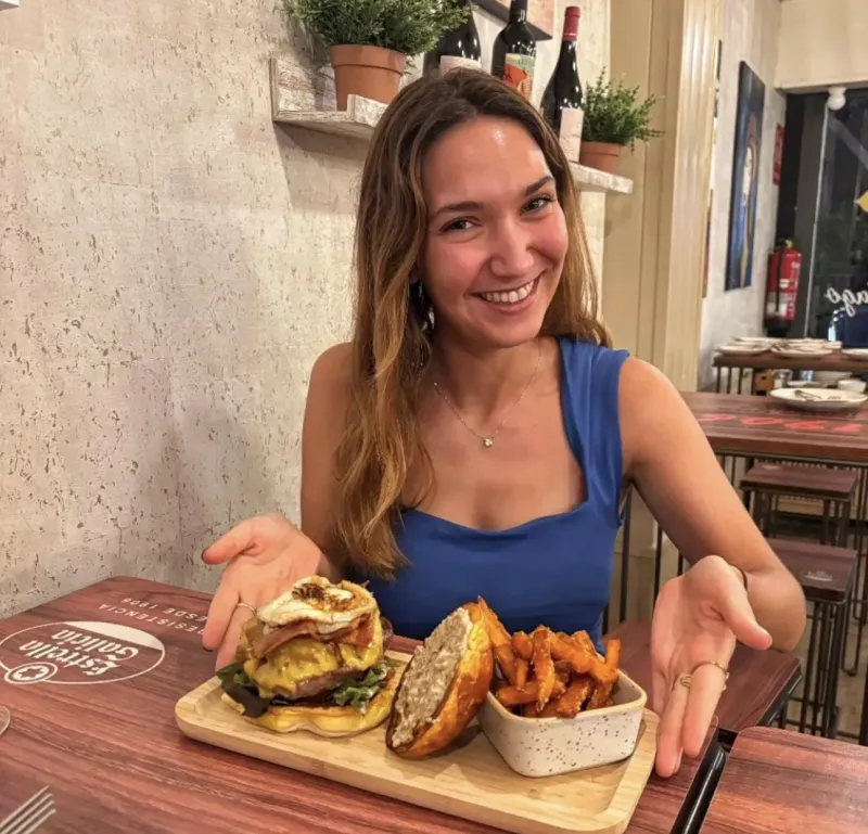 Clienta disfrutando de una hamburguesa gourmet en la terraza